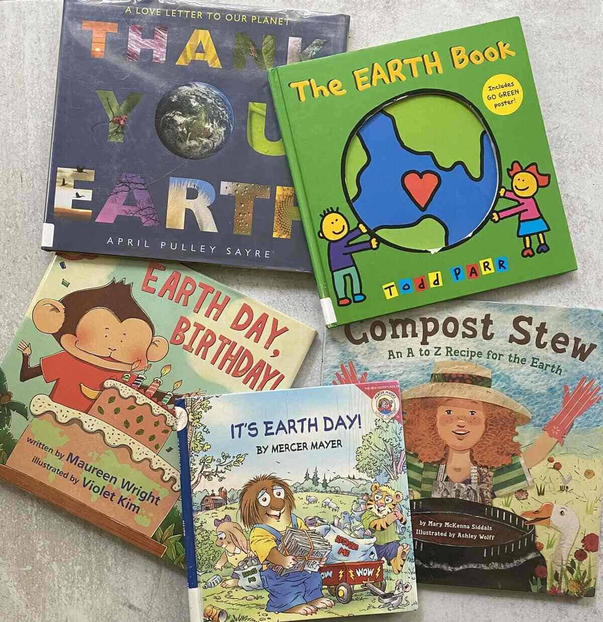 Five kid-friendly Earth Day books laid out on a gray board.
