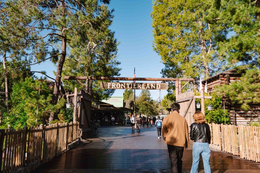 Entrance to Frontierland with overhead sign and wooden posts lining the walkway; one of the many lands in Disneyland Resort