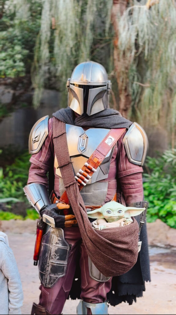 Mandalorian and Grogu posing for a photo in Disneyland's Star Wars Land also known as Batuu or Galaxy's Edge