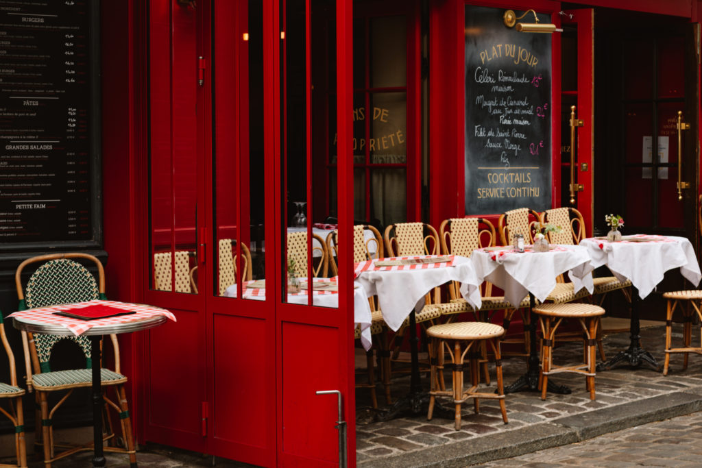 Paris cafe with red walls and wicker chairs, tables, and stools